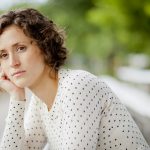 Worried woman sitting on bleachers outside