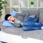 brunette woman in pain laying on sofa