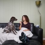 brunette woman sitting on sofa with her dog