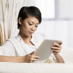 chinese woman sitting on sofa at home using tablet