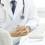 doctor with hand crossed sitting at desk speaking with patient