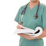 doctor with stethescope around neck holding medical book