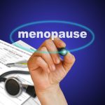 menopause writing with paperwork on blue background