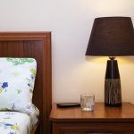 nightstand with glass of water next to bed with floral sheets