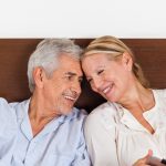 older couple smiling at home in their bed