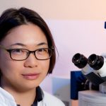 oriental researcher in her lab by microscope