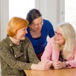 three middle aged friends sitting at kitchen table