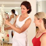 two women discussing bone health in front of a spine