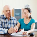 wife helping husband while sitting at kitchen table