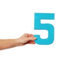 woman holding out blue number 5 on white background
