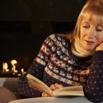 woman inside during winter by fire reading book