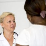 woman speaking to her doctor in an exam room