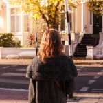 young brunette women walking in neighborhood waiting at crosswalk