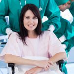 young woman patient in wheelchair being pushed by nurse